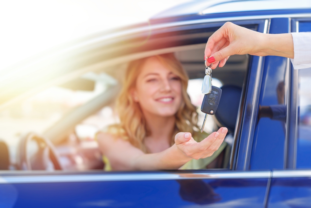 A woman's hand passes the key to the car. Buying a car or renting.