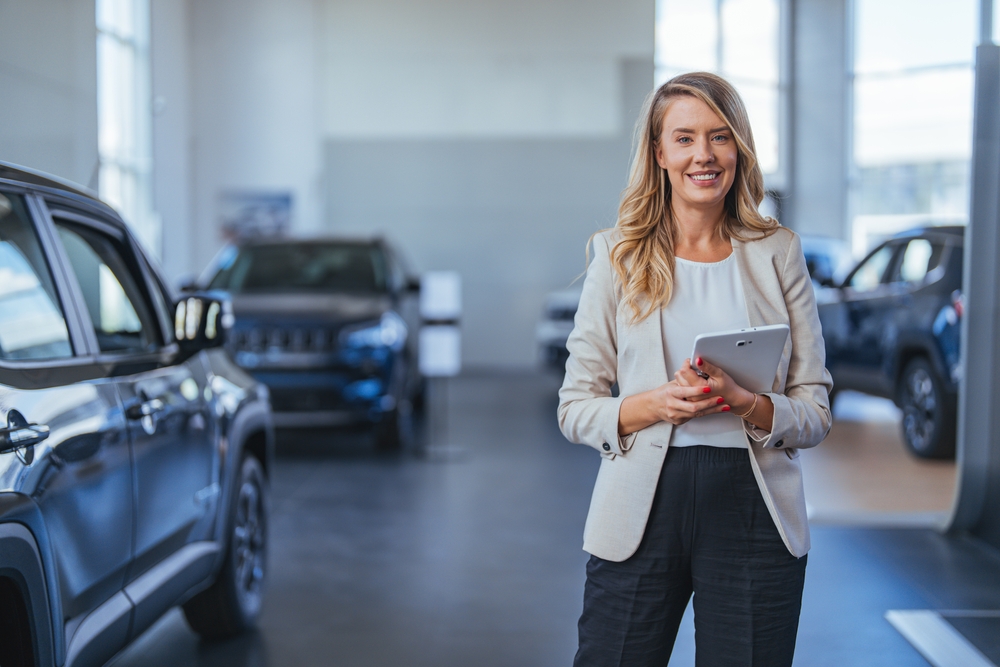 Portrait of a female car saleswoman working in the showroom. Close up of a businesswoman offering a handshake in the showroom